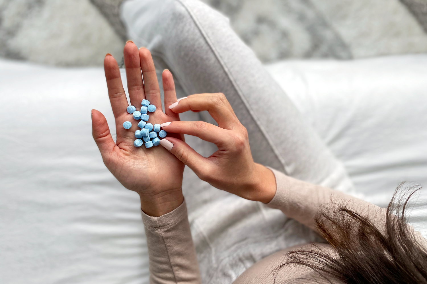 Young woman holding some Mouthwash Tabs as she chooses one with her other hand